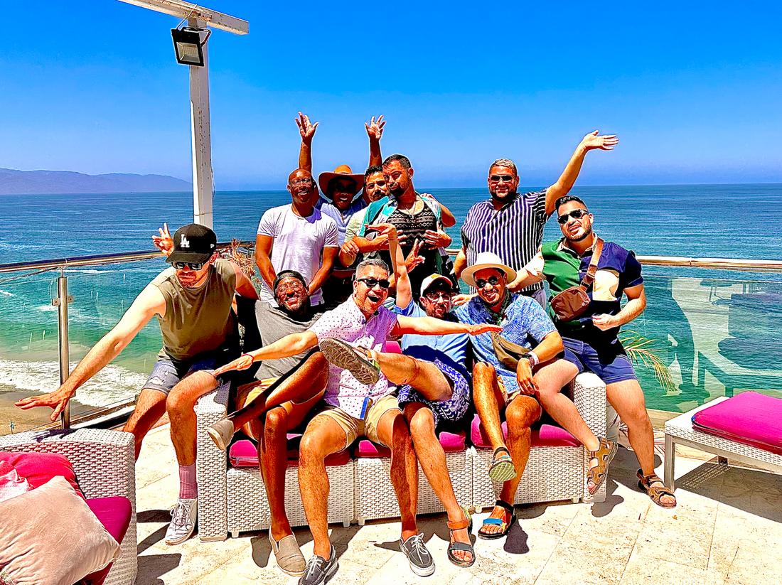 A group of diverse friends wearing Chico Lindo’s Out and Proud T-shirts, laughing and celebrating LGBTQ+ pride.