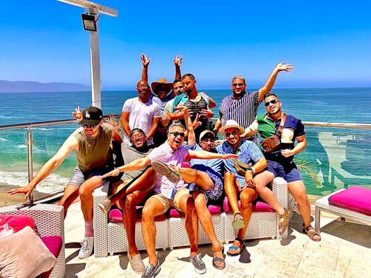 A group of diverse friends wearing Chico Lindo’s Out and Proud T-shirts, laughing and celebrating LGBTQ+ pride.